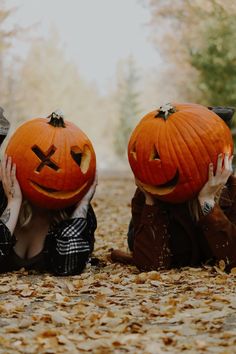 two children with pumpkins on their heads sitting in the leaves