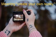 a person holding up a camera to take a photo with their hand and wrist tattoos