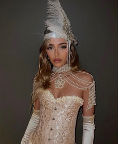 a woman in a corset with pearls and feathers on her head is posing for the camera