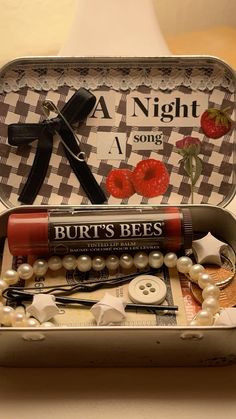 an open tin box filled with different types of sewing tools and buttons on top of a table