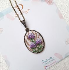 an embroidered necklace with purple flowers on it