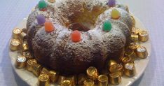 a bundt cake covered in candy and candies on a white plate with gold decorations