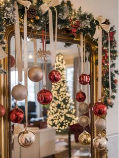 a mirror with ornaments hanging from it in front of a christmas tree