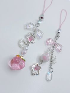 two pink and white necklaces with charms on them