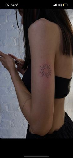 a woman with a small sun tattoo on her arm