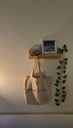 a white bag hanging on a wall next to a shelf with a plant in it