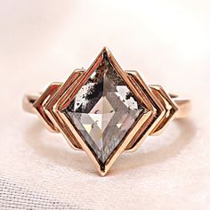 a ring with a diamond on it sitting on top of a white cloth covered table