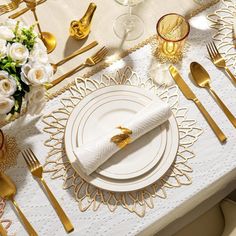 the table is set with gold and white plates, silverware, and napkins