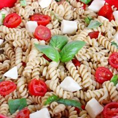 pasta salad with tomatoes, mozzarella and parmesan cheese in a red bowl