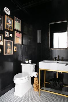 a white toilet sitting next to a sink in a bathroom under pictures on the wall