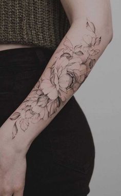 a woman's arm with flowers tattooed on the left side of her arm and wrist