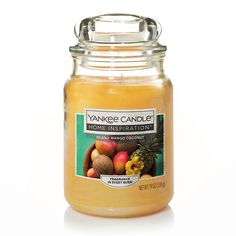 a large jar filled with orange and pineapple flavored candles on a white background