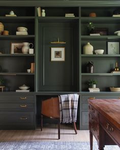 a room filled with lots of green bookshelves next to a table and chair