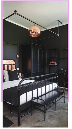 Modern black-themed bedroom with metal bed frame, industrial light fixture, and minimalist decor.