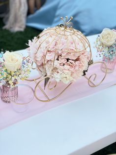 pink flowers in vases are sitting on a table with a decorative birdcage