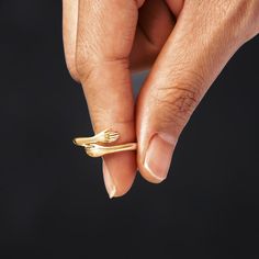 a person is holding a gold ring in their left hand and it has two fingers on the other side