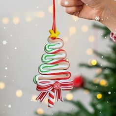 a hand holding a christmas ornament in front of a tree