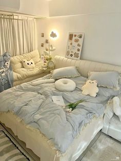 a bed with pillows and stuffed animals on it in a room that has white walls