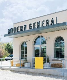 modern general store front with yellow door and metal railings on the side walk way