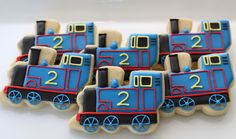 some cookies shaped like trains are sitting on a table with blue and red icing