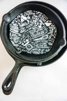 an old cast iron skillet with writing on the inside and outside, sitting on a white surface