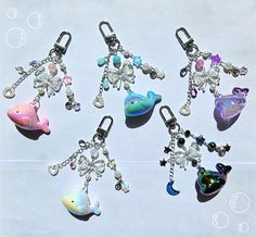 six different keychains with charms attached to them on a white surface, one is shaped like a dolphin and the other has a fish