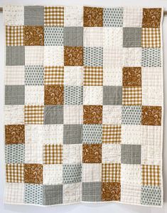 a patchwork quilt hanging on a clothesline with white and brown plaids in the background