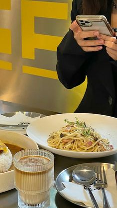 a woman taking a selfie with her cell phone at a table full of food