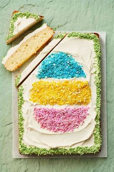 a cake with white frosting and colorful sprinkles on it next to a slice of bread