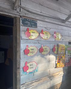 signs on the side of a wooden building with thumbs up and down pointing to different languages