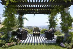 an outdoor seating area with chairs and greenery on the roof, in front of a beautiful view