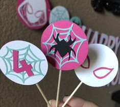 a person holding up some cupcake toppers with spider webs on them