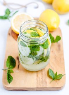 a mason jar filled with cucumbers and lemons on a cutting board next to sliced lemons