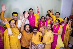 a group of people dressed in yellow and pink are posing for a photo with their hands up