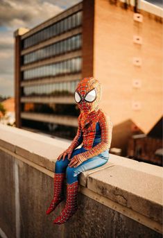 a spider man sitting on top of a cement wall