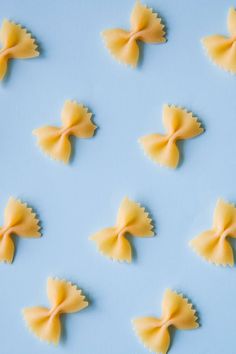 small pasta bows are arranged in the shape of butterflies on a blue background with copy space