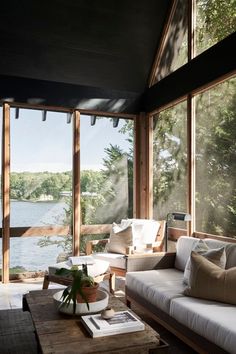 a living room filled with furniture and large windows overlooking the water in front of it