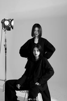 two women sitting in front of a camera and posing for a black and white photo