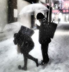 two people are standing in the snow with umbrellas over their heads and looking at each other