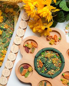 a wooden clock sitting on top of a table next to flowers