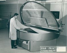 black and white photograph of a man looking into a machine