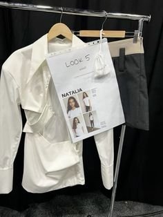 a white shirt hanging on a clothes rack next to a black and gray suit hanger