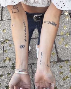 two people with tattoos on their arms and legs, both holding hands in the air