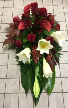 a bouquet of red and white flowers sitting on the ground next to a tile floor