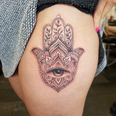 a woman's thigh with an ornate hamsa tattoo on the side and eye in the middle