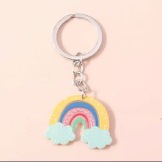 a keychain with a rainbow and clouds painted on the front in pastel colors