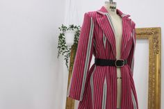 a mannequin wearing a red and white striped coat on display in front of a mirror