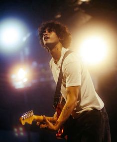 a young man playing an electric guitar on stage