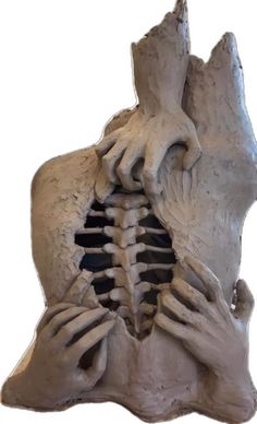 a sculpture of two hands holding the back of a human skeleton, with one hand on it's chest