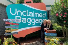 two women standing in front of the unclaimed bagage sign with suitcases